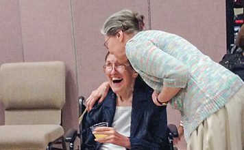 Sallie Satterthwaite (seated in wheelchair) receives a greeting from a friend at a reception in her honor Sept. 24, 2017, at Christ Our Shepherd Lutheran Church in Peachtree City. Photo/Cal Beverly.
