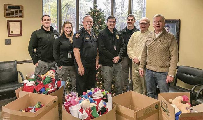 Carrying on a Peachtree City tradition of giving — Doing their part for the Peachtree City Police Department’s annual Light Up the Night Toy Drive for needy kids are, from left, department staff Ryan MacCallum, Heather Scott, Stan Pye, Steven Stoyell and Gary Meier, joined by Beechwood subdivision residents Jerry Neese and Denny Spaulding, who have carried on the practice of supplying Christmas stocking for needy kids, an effort started in the early 1990s by the late David Hanahan. Photo/Peachtree City Police Department.