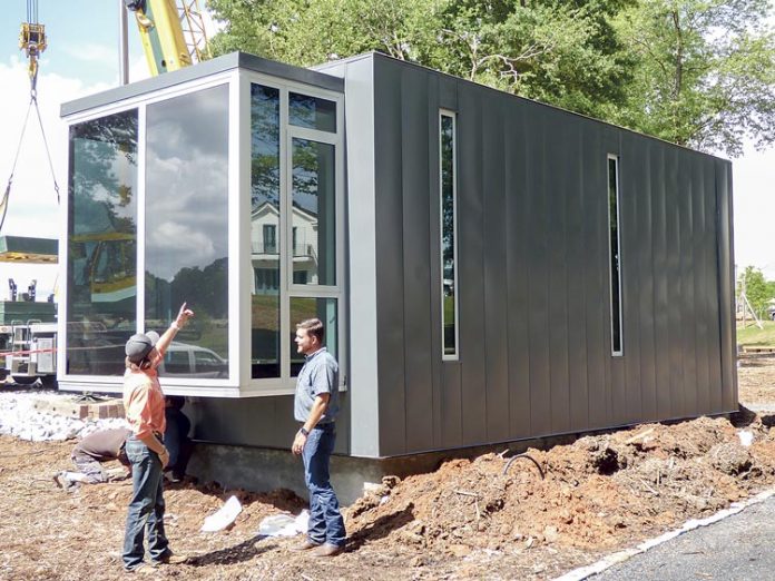 Kasita, Inc. representative Matt Hensley, left, and Pinewood Forest Builders Guild Director Brett Baker inspect the new Kasita micro-home delivered to Fayetteville on May 17. Photo/Ben Nelms.