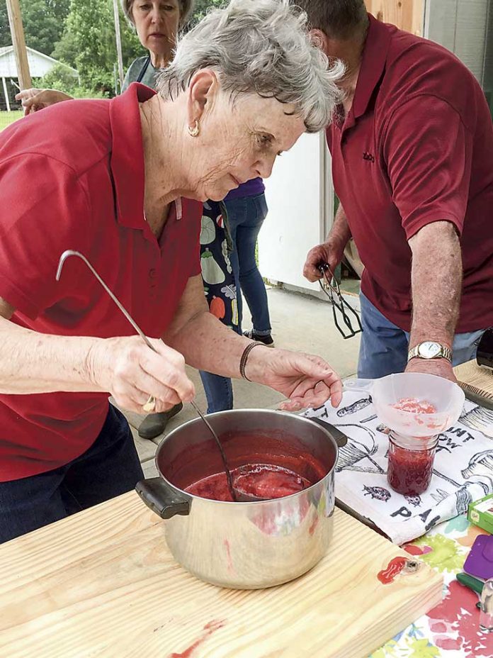 Hopewell UMC member, Beth James, carefully fills jars with freshly made strawberry jam. The strawberries come from the Tyrone church’s garden and members and neighbors pitch in to can the harvest. Photo/Sandy Golden.