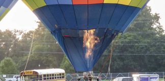 Firing up for high-flying fun — Passengers grab onto the basket rails in preparation for their hot-air balloon ascent Saturday south of Fayetteville as lines of riders await their turns. Thousands turned out for the annual county event. Photo/Ben Nelms.