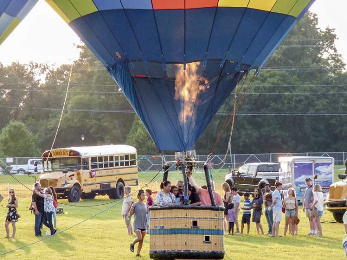 Firing up for high-flying fun — Passengers grab onto the basket rails in preparation for their hot-air balloon ascent Saturday south of Fayetteville as lines of riders await their turns. Thousands turned out for the annual county event. Photo/Ben Nelms.