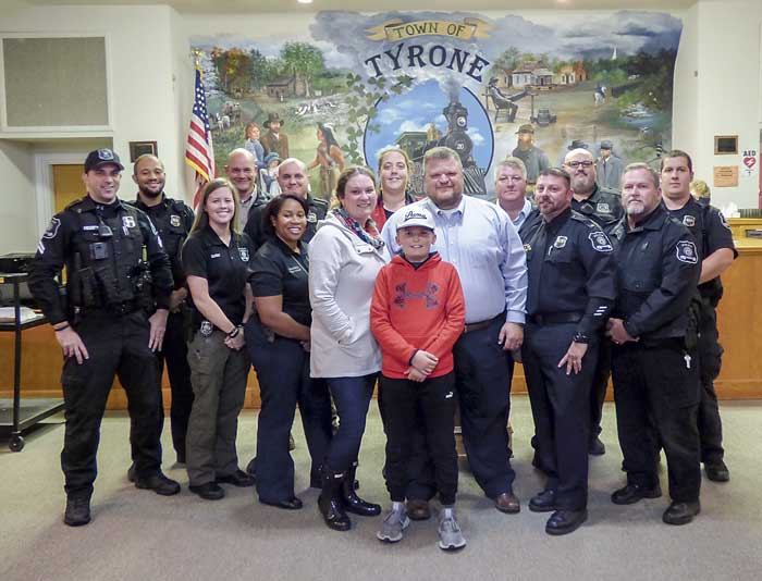 Former Tyrone Police Chief and new Town Manager Brandon Perkins (center) was joined by wife, Amy, and son, Cooper, at the Nov. 15 meeting of the Town Town Council. They are accompanied by members of the Tyrone Police Department. Photo/Ben Nelms.