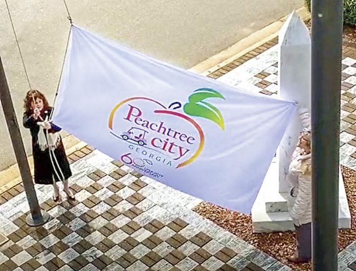 Peachtree City Mayor Vanessa Fleisch (L) raises the official city flag at City Hall Plaza in preparation for the city’s 60th anniversary party at Drake Field March 9. Photo/Submitted.