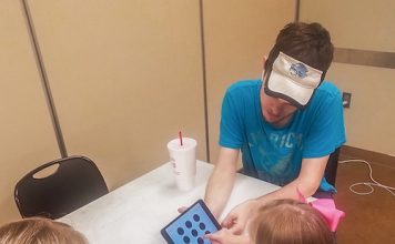 Below, Fayette County Community Youth Football member Nick Brown works with a youngster taking the concussion baseline test given to the organization’s football players and cheerleaders. Photo/Submitted.