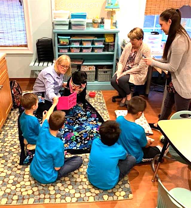 Becky Hall, certified therapy dog trainer, reads to the Lower School class with therapy dog Libby, while teacher Caroline Breslin (from left) and teacher assistant Martha Butler look on. Photo/Submitted.