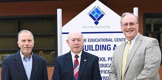 Former Fayette County Public School superintendents Dr. John DeCotis and Trigg Dalrymple take their place alongside current Fayette County Public School Superintendent Dr. Joseph Barrow in front of the school system’s new logo. Photo/Fayette School System.