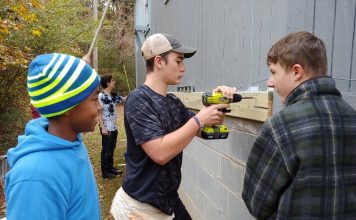 The Foundry High School students working at the home of Fayetteville Vietnam veteran MacArthur Starr as a way to honor him included, from left, Najeh Hanif, Jackson Mayer and Tanner Tatum; with Reese Wackes in the rear. Photo/Submitted.