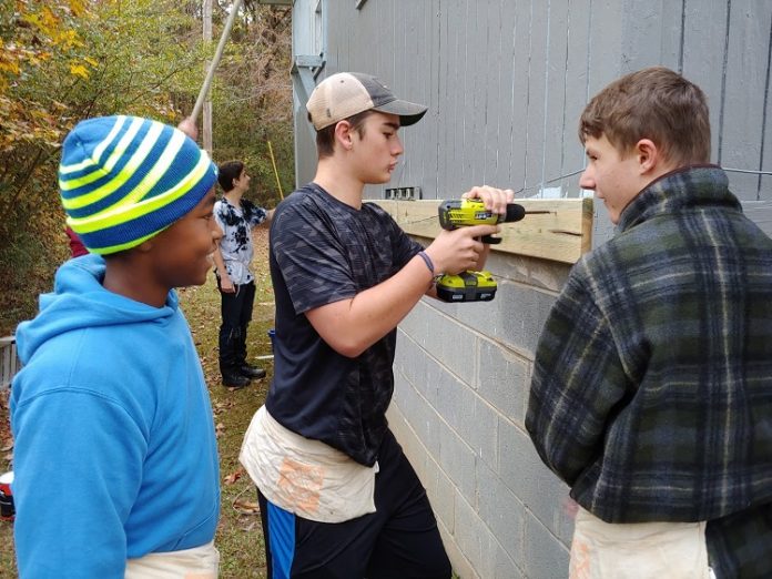 The Foundry High School students working at the home of Fayetteville Vietnam veteran MacArthur Starr as a way to honor him included, from left, Najeh Hanif, Jackson Mayer and Tanner Tatum; with Reese Wackes in the rear. Photo/Submitted.