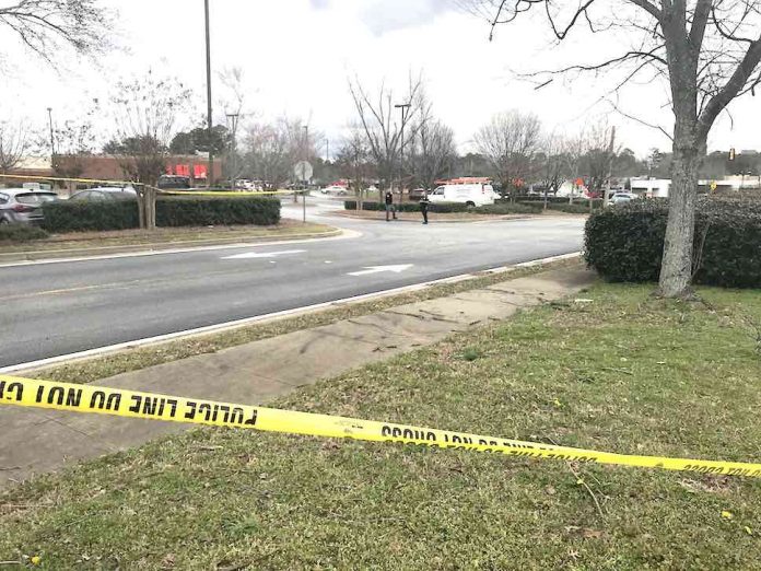 Fayetteville police are shown behind a police tape in a restaurant parking lot off Hwy. 85 jto the north of the shooting incident Monday. Photo/Ben Nelms.