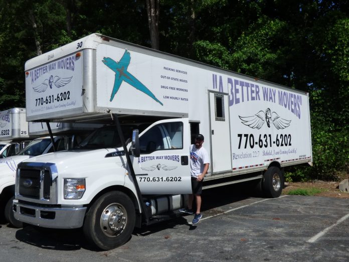A Better Way Movers Office Manager John Kidney with one of the signature moving trucks at the company's Peachtree City location on Dividend Drive. Photo/Ben Nelms.