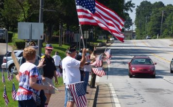 Patriotism was alive and well in Fayetteville on July 4, as members of Fayette County American Legion Post 105 lined South Glynn Street in front of the Log Cabin, waving flags and being recognized by the many motorists honking their horns in support. Photo/Ben Nelms.