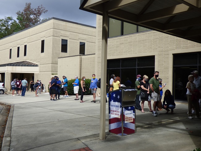 <b>Voters in line at the Peachtree City Library for the first day of early voting had the line extended up Willowbend Road and into the City Hall parking lot. Photo/Ben Nelms.</b>