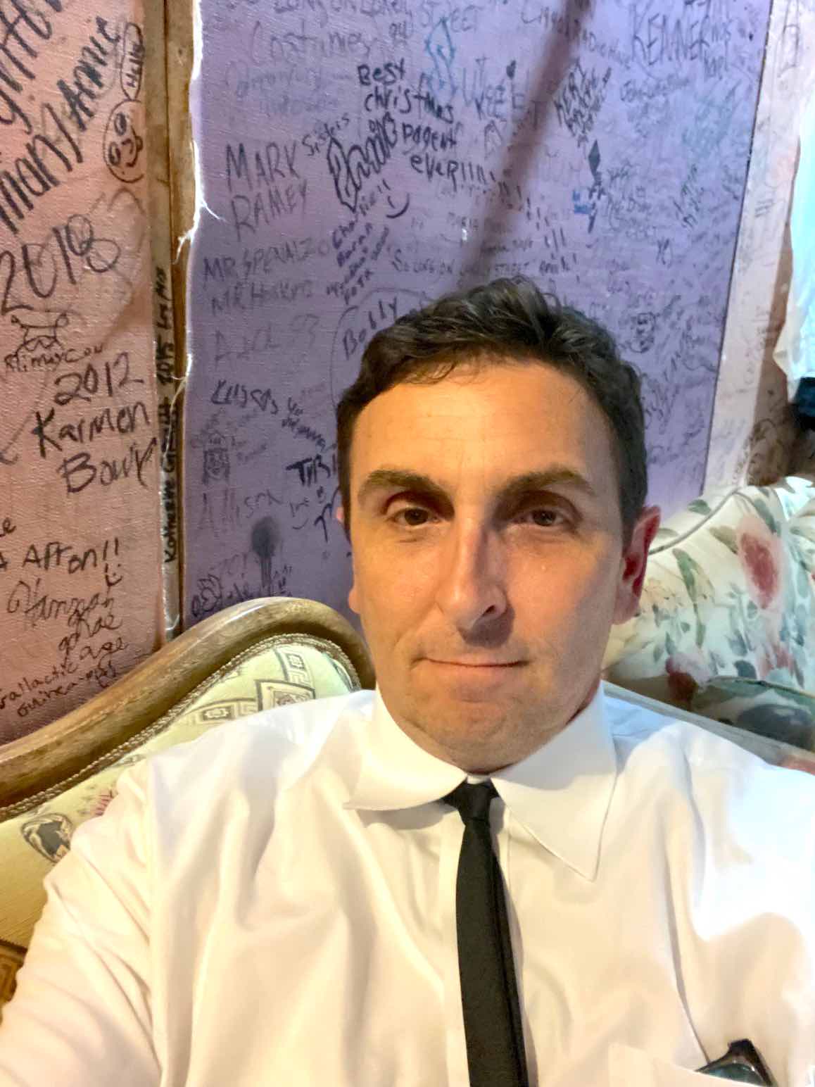 Michael Boylan of Fayetteville, a volunteer with the Southside Theatre Guild, sits in front of hundreds of signatures of former cast members on the theatre's dressing room walls. Photo/Michael Boylan.