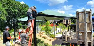 Workers install sunshade over popular hillside slide in Fayetteville City Center Park.