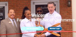 Fayette Chamber of Commerce President Colin Martin (at right, holding scissors) helps cut the ribbon opening a new business. Fayetteville Mayor Ed Johnson is at left. Photo/Fayette Chamber website.