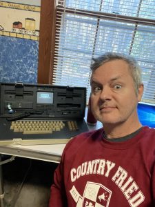 The author with a vintage portable computer from 1982, the Osborne I (still works) with 64K RAM, Z80 processor, two 5 1/4&quot; floppy disk drives, and a 300baud modem. Photo/Joe Domaleski