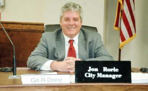 New city manager Jon Rorie next to his favorite sign.  Photo/Ben Nelms.